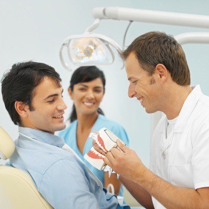 Close-up of dentist and dental nurse showing patient how to wash teeth